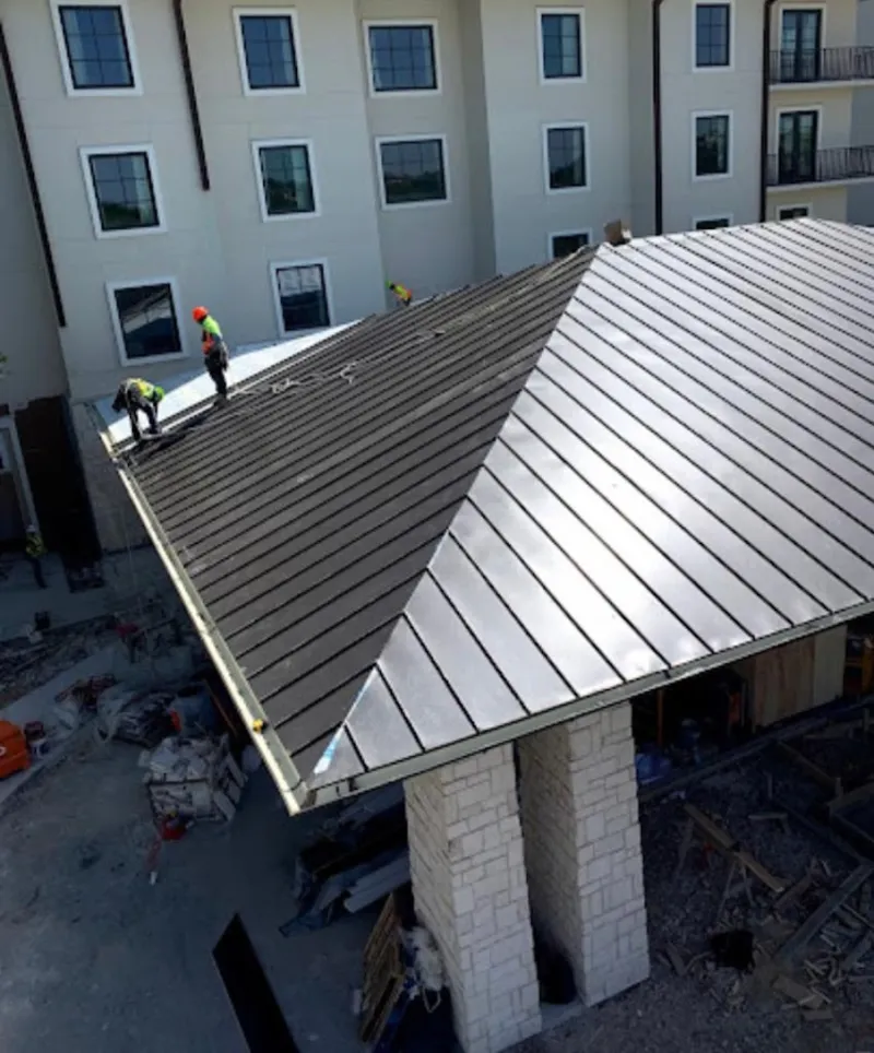 Crew installing standing seam metal roof panels on a commercial project in Brea